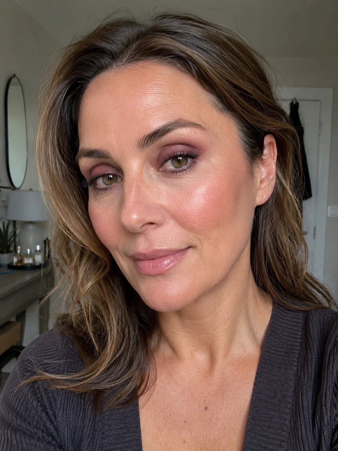 Mulher com sombra ameixa esfumada e pele luminosa num look elegante e natural depois dos 50