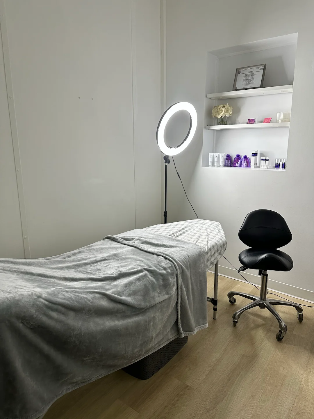 Sala de tratamentos de beleza preparada, com marquesa, banco e cadeira de atendimento vazios.