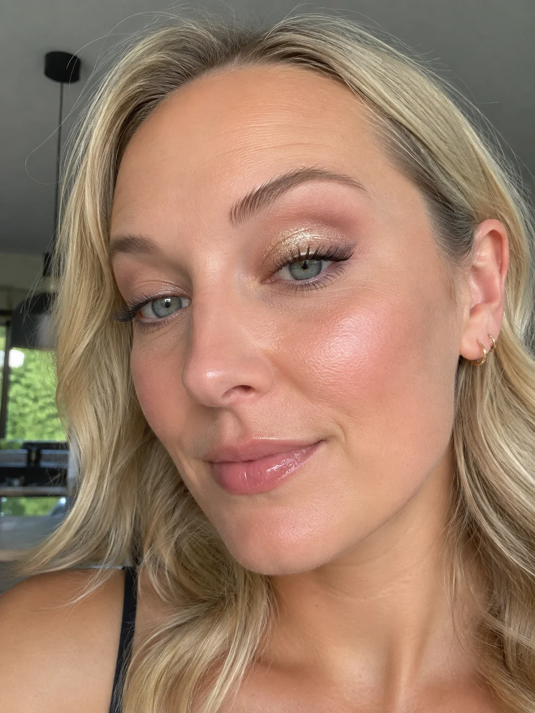 Mulher com sombra de olhos dourada com glitter concentrada na pálpebra móvel.