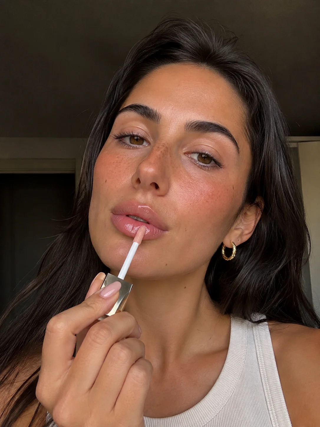 Mulher com maquilhagem natural e gloss labial, tendência de beleza 2026