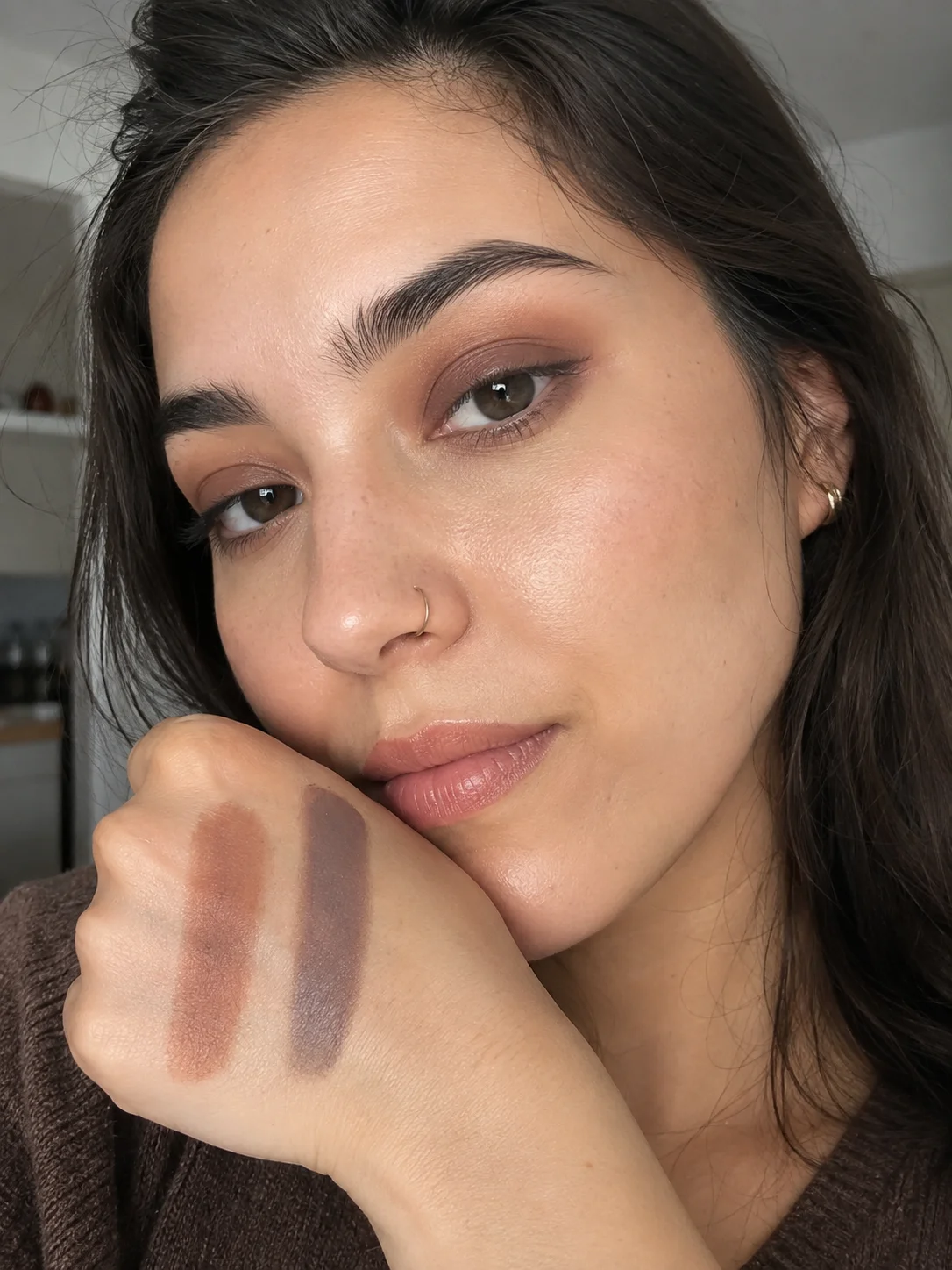 Mulher a mostrar dois tons de sombra neutra, castanho e taupe, no dorso da mão.