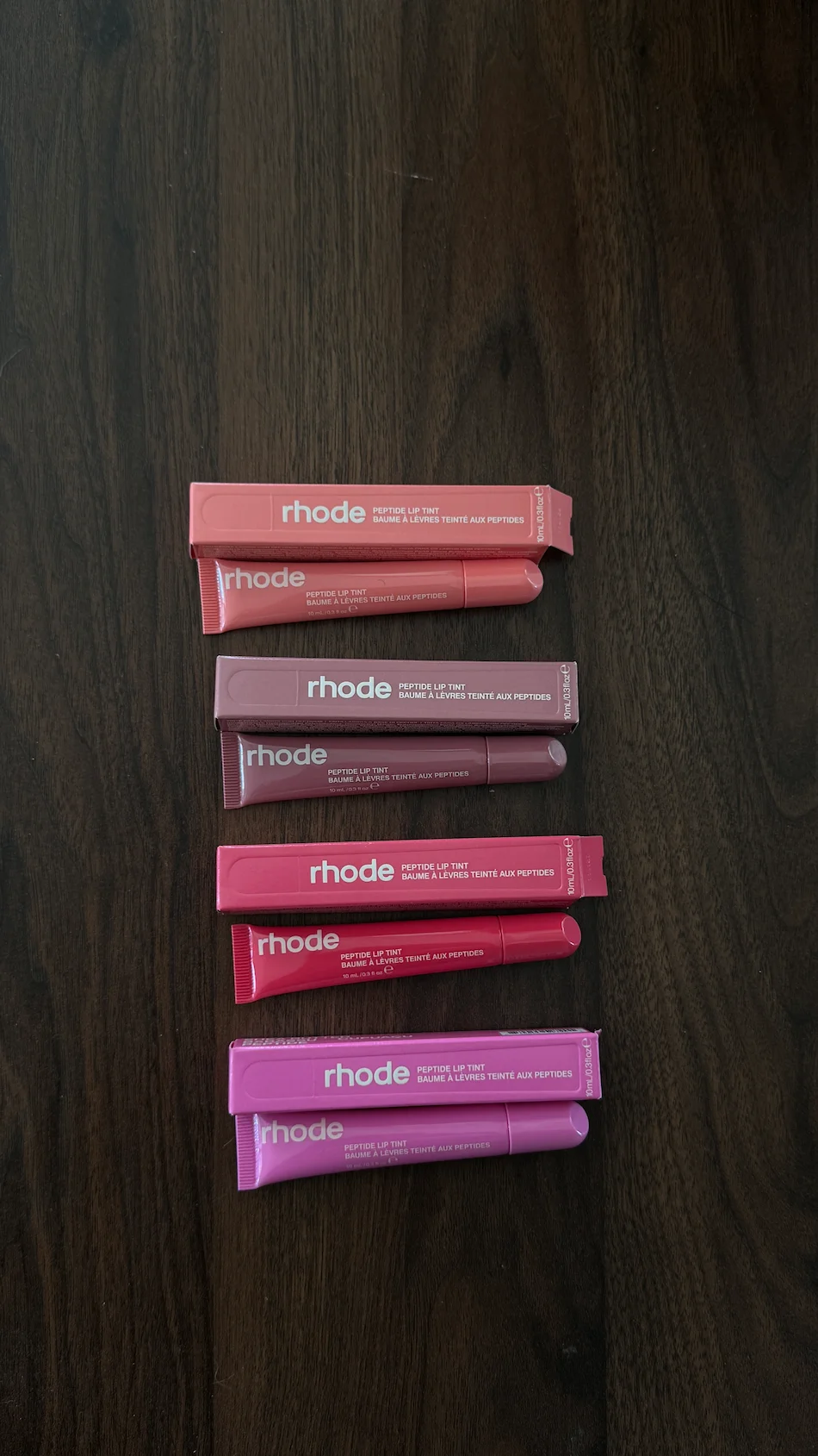 Quatro Peptide Lip Tint da Rhode em diferentes tons rosa e malva, com as respetivas embalagens