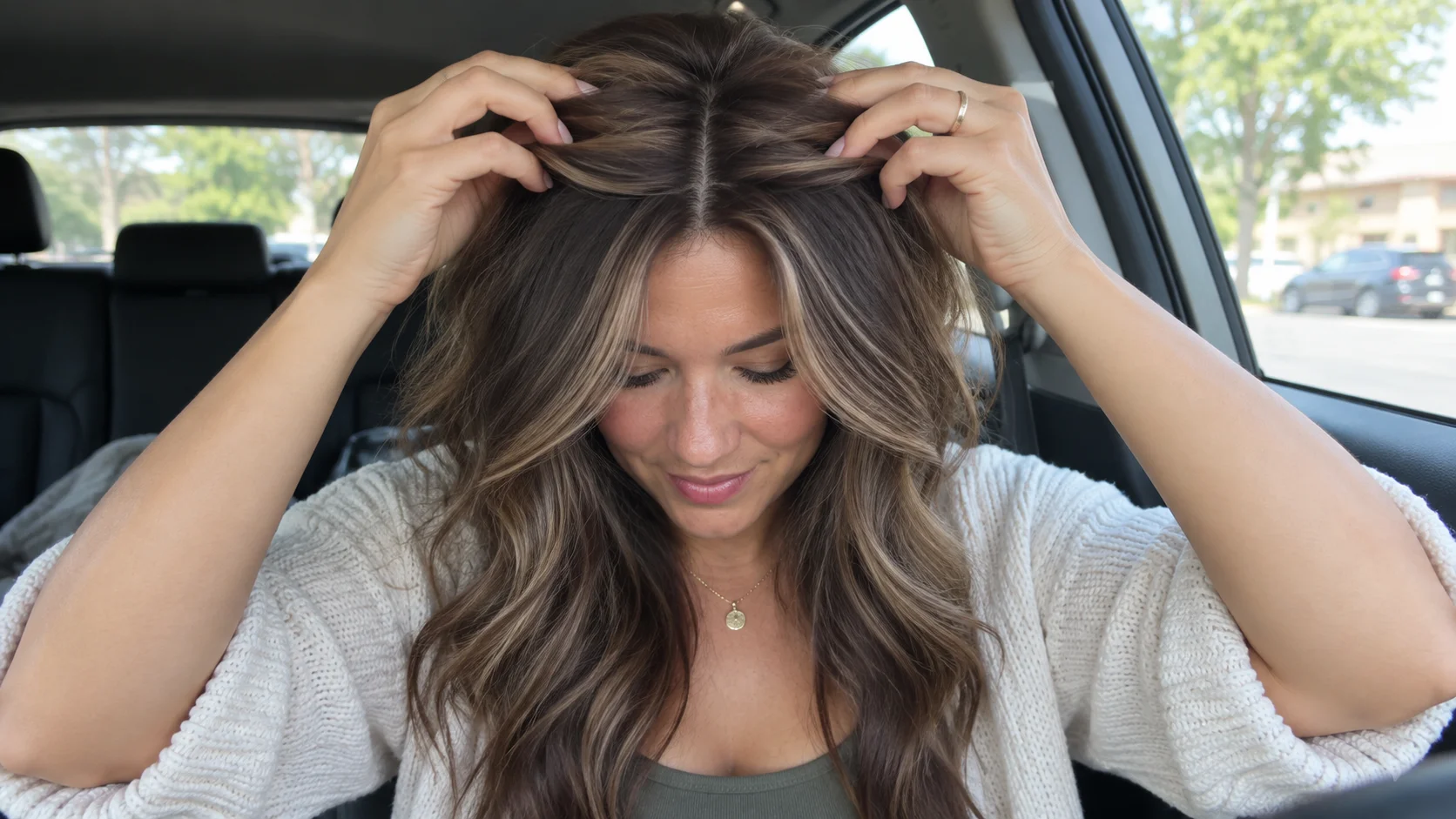 Mulher sentada num automóvel a levantar o cabelo junto à risca, mostrando volume natural e integração no topo da cabeça.